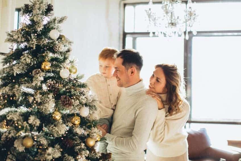 woman man and child decorating Christmas tree