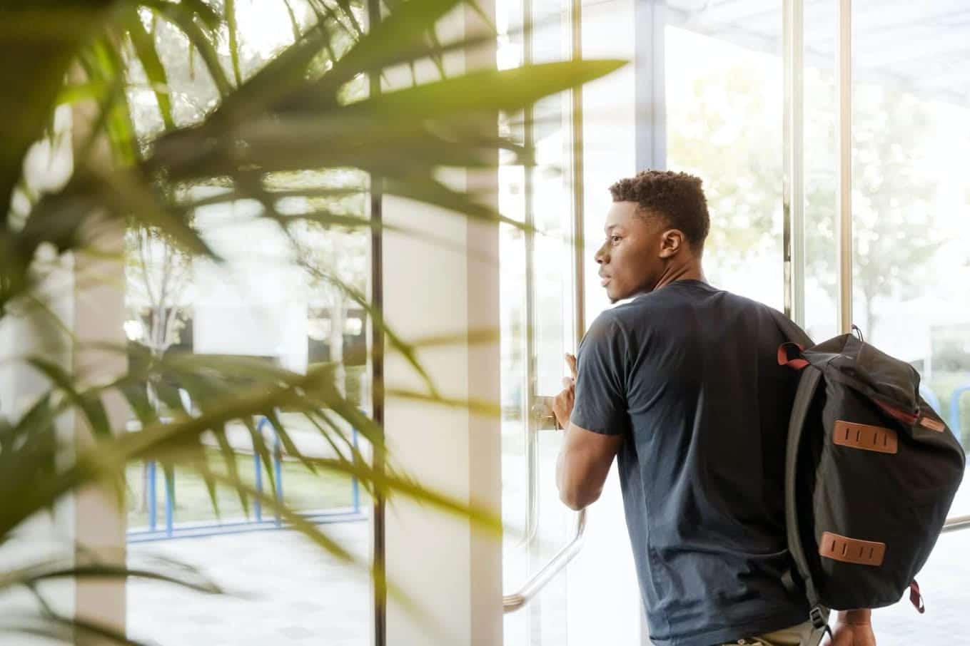 Window film in schools protects students like this African American adolescent exiting through a glass door armed with window film.