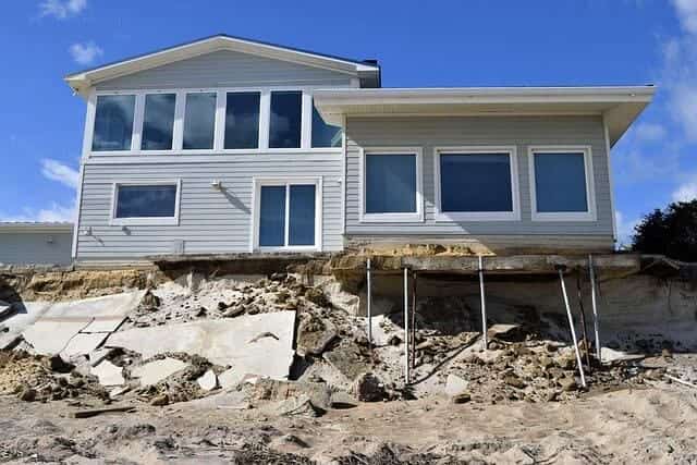 Coastal home left on eroded ground after a storm with its large windows still intact