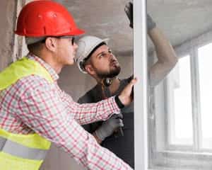 A couple of contractors installing a window.
