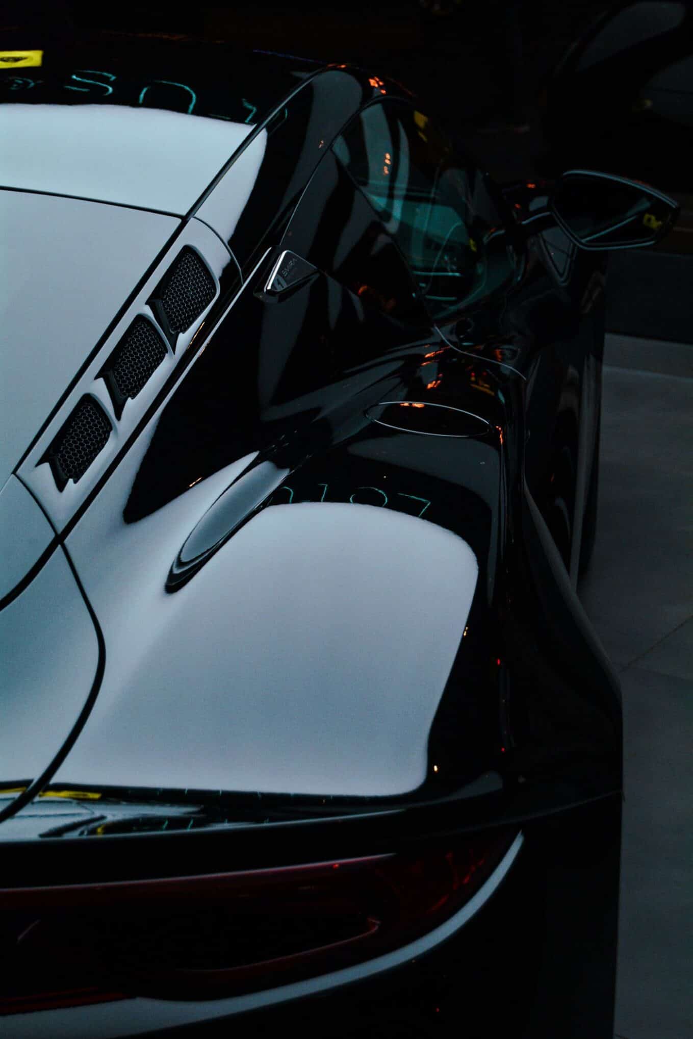Glossy black sports car with deep reflections, the kind of finish paint protection film is designed to preserve