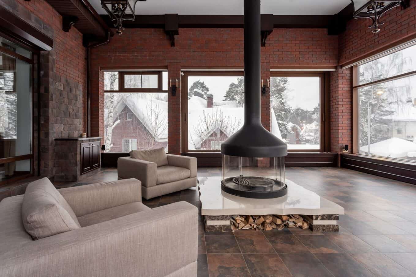 Living room with a fireplace and large windows overlooking a snowy landscape, where insulating window film helps hold heat in