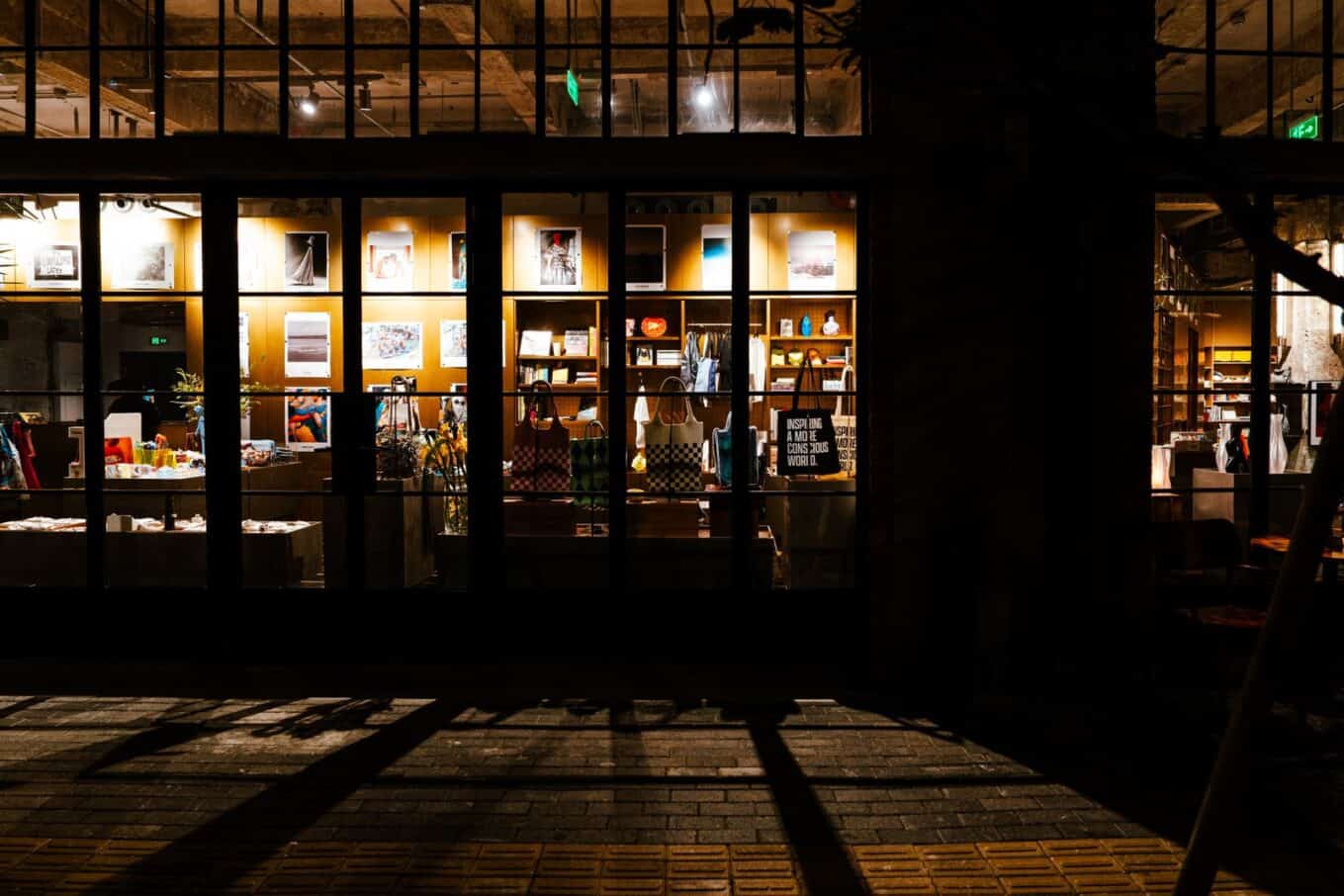 Lit storefront with large glass windows on a dark city street at night