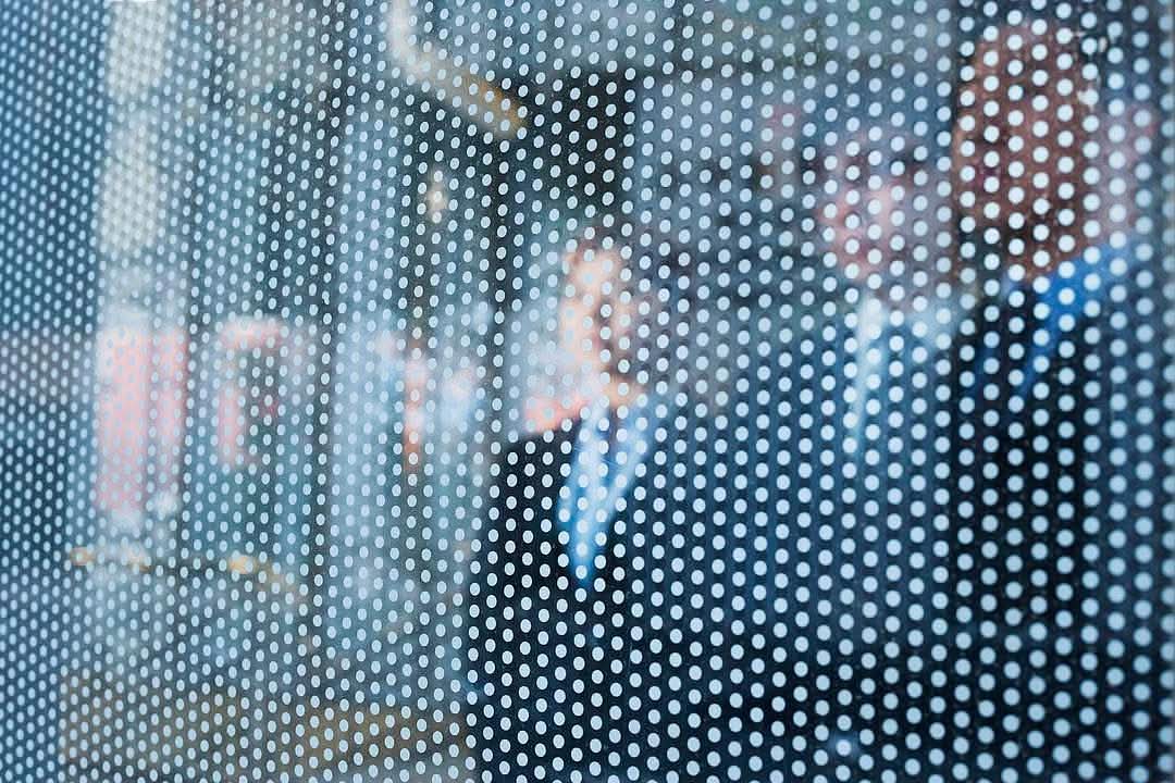 Three business people behind a glass wall looking out